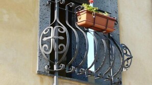 A window with a wrought iron gate and a hanging planter with flowers. - Serra San Biagio (Calatabiano)