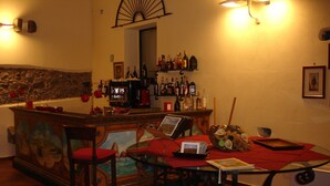 A bar area with a mural, bar stools, and a dining table with chairs. - Serra San Biagio (Calatabiano)