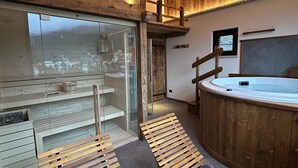 Un interior de madera con un jacuzzi, bancos de madera y un muro de cristal con vistas.