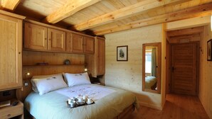 Un dormitorio de cabaña de madera con una cama, mesitas de noche y un armario de madera.