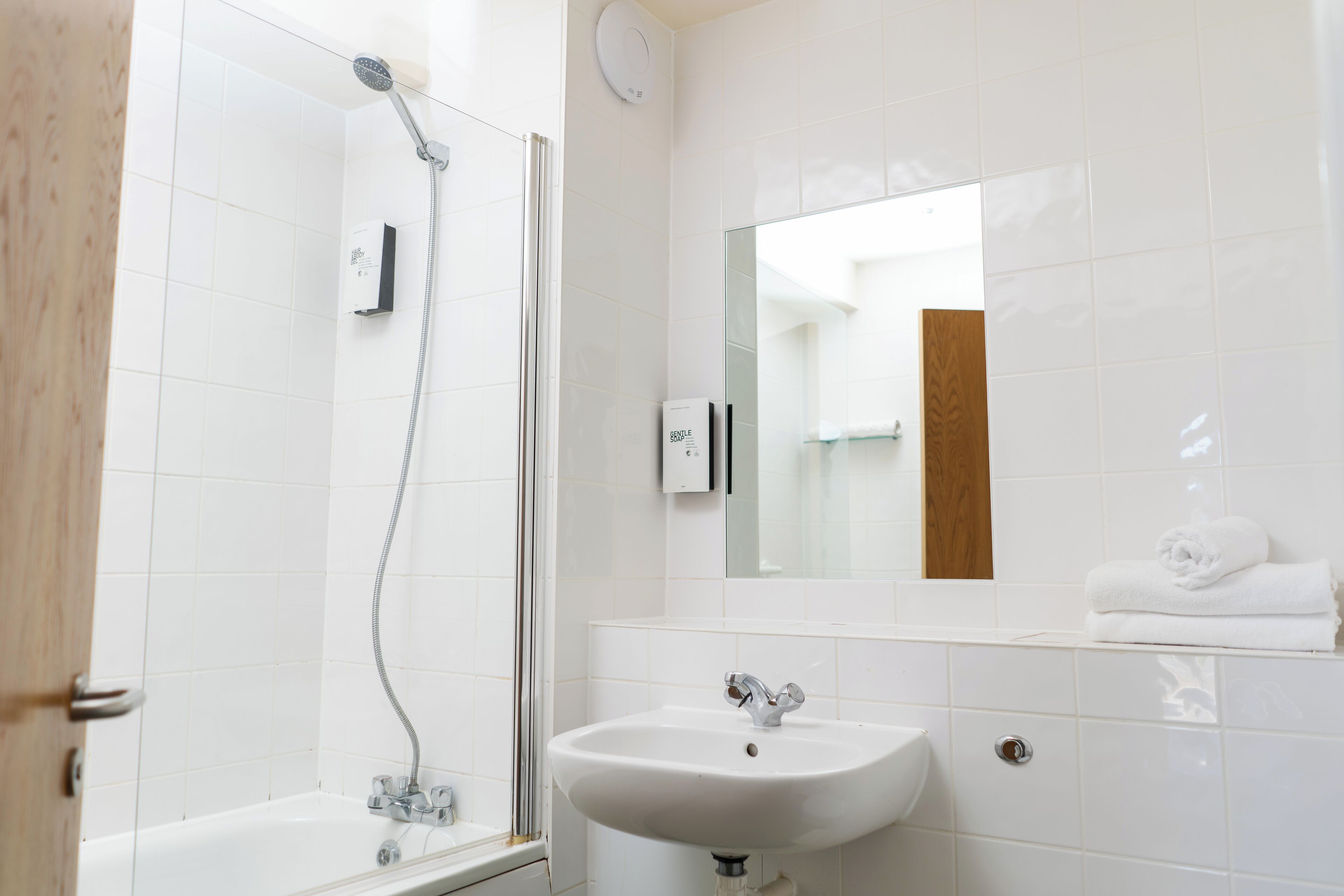 Une salle de bain avec une douche, un lavabo et un miroir.