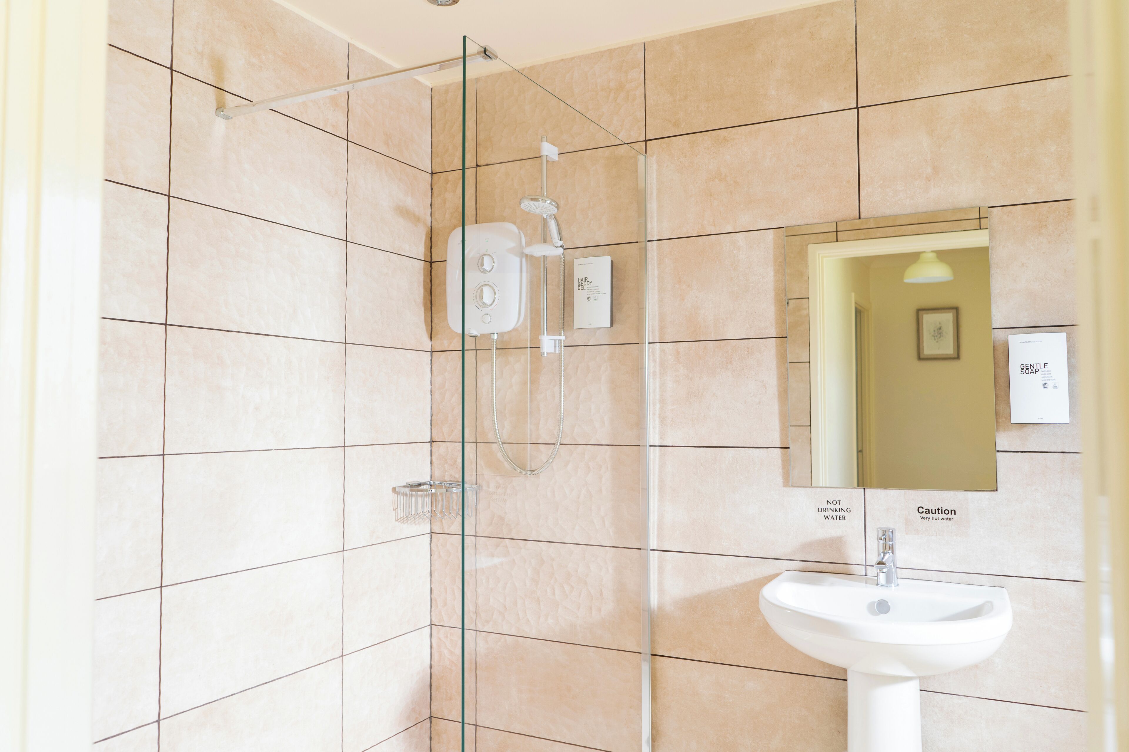 A modern bathroom with a glass-enclosed shower, a white sink, and a mirror.