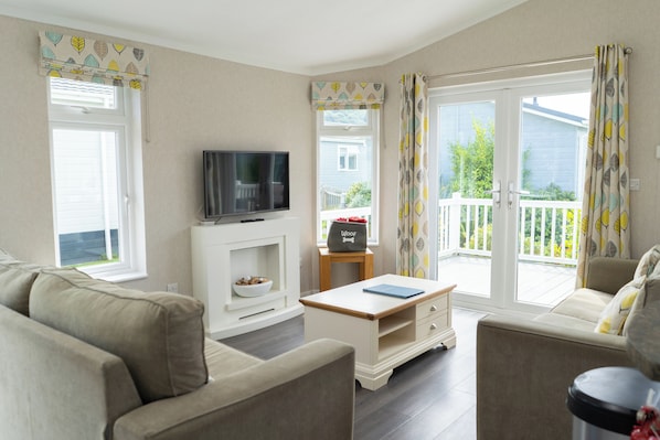 A living room with a sofa, a coffee table, a television, and a small table with a basket labeled 'Woof'.