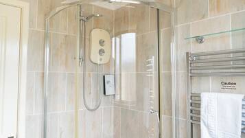 Ducha con cabezal de ducha de mano, panel de control y puerta de vidrio.