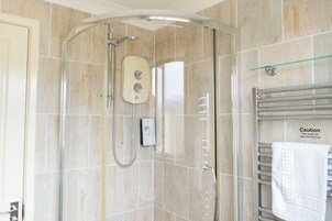 Ducha con cabezal de ducha de mano, panel de control y puerta de vidrio.