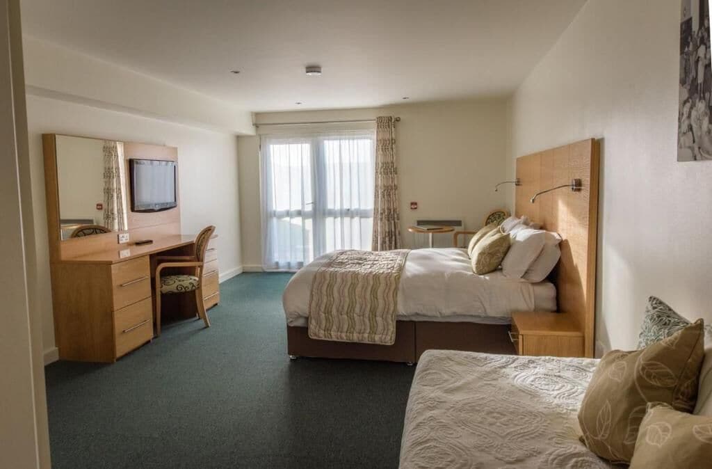 Ein Hotelzimmer mit Bett, Schreibtisch, Stuhl und Fernseher.