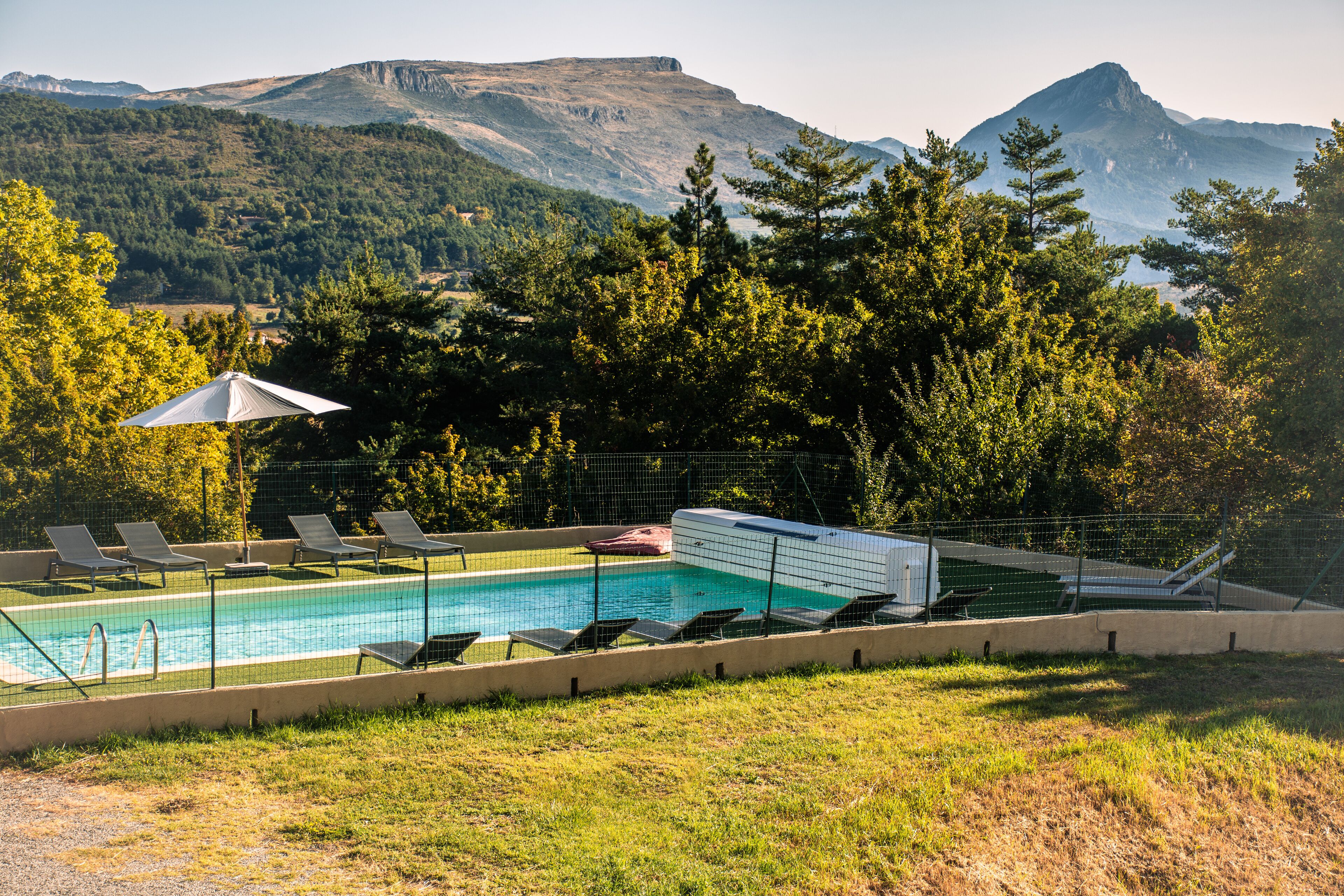 Una piscina al aire libre, sombrillas, sillones reclinables de piscina