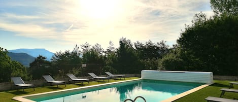 Een buitenzwembad, parasols bij het zwembad en ligstoelen