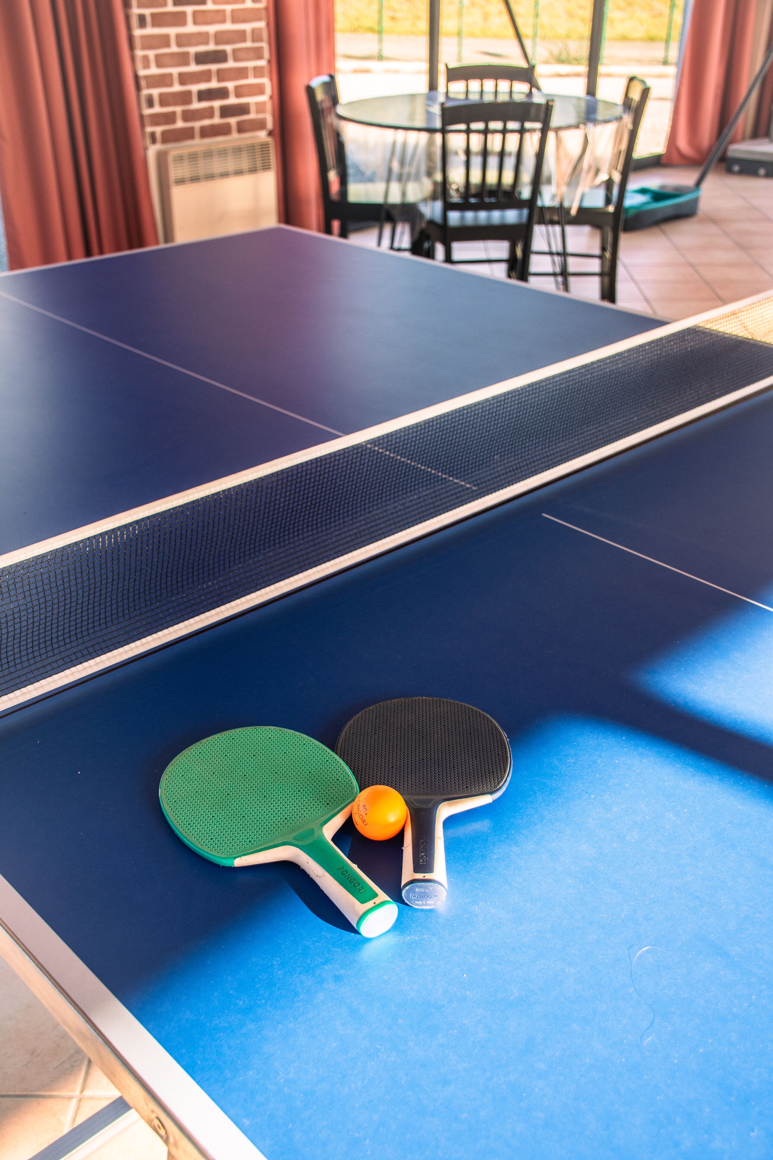 A ping pong table with two paddles and a ball.