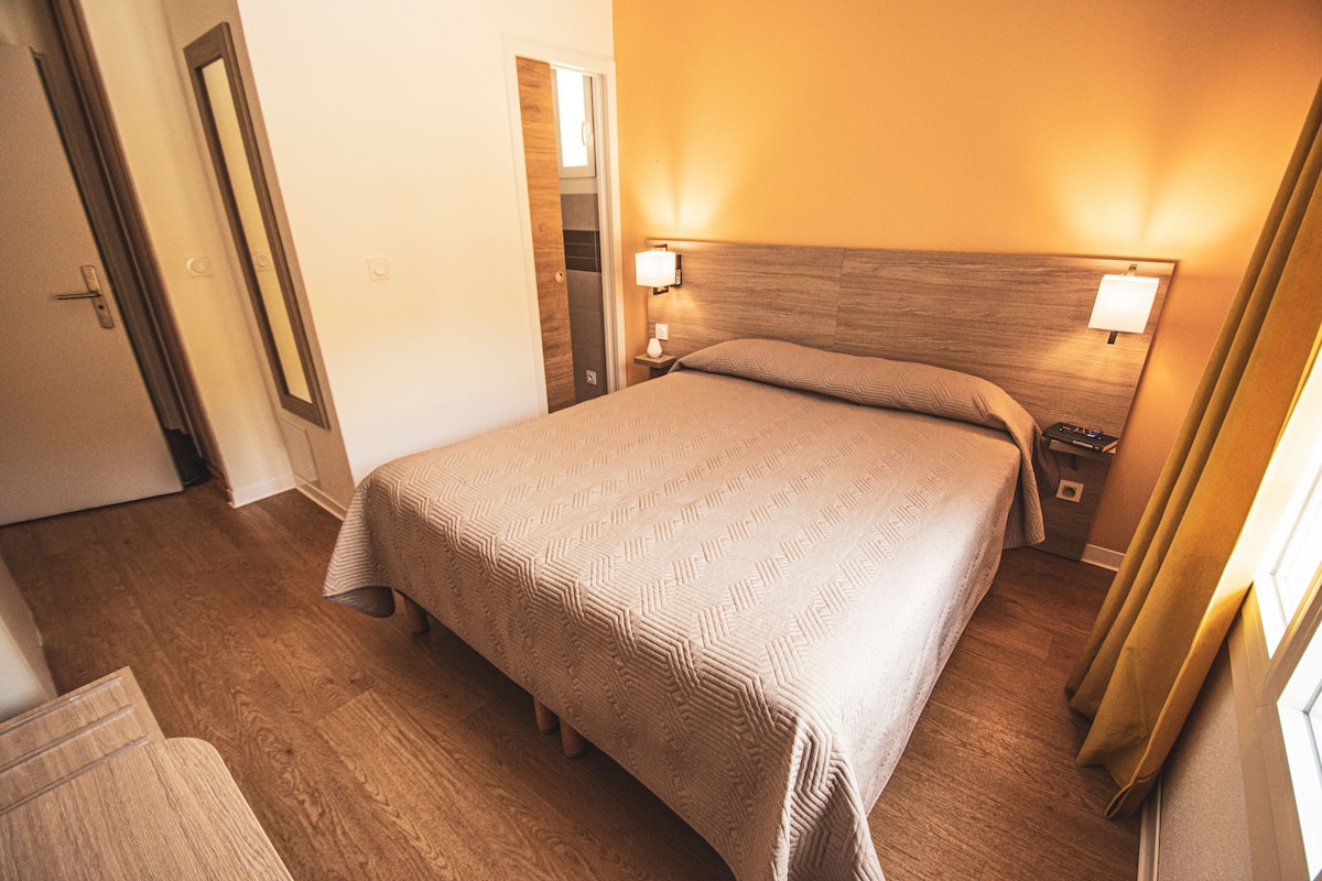 A hotel room with a large bed, bedside lamps, a wooden headboard, and a door leading to a closet.