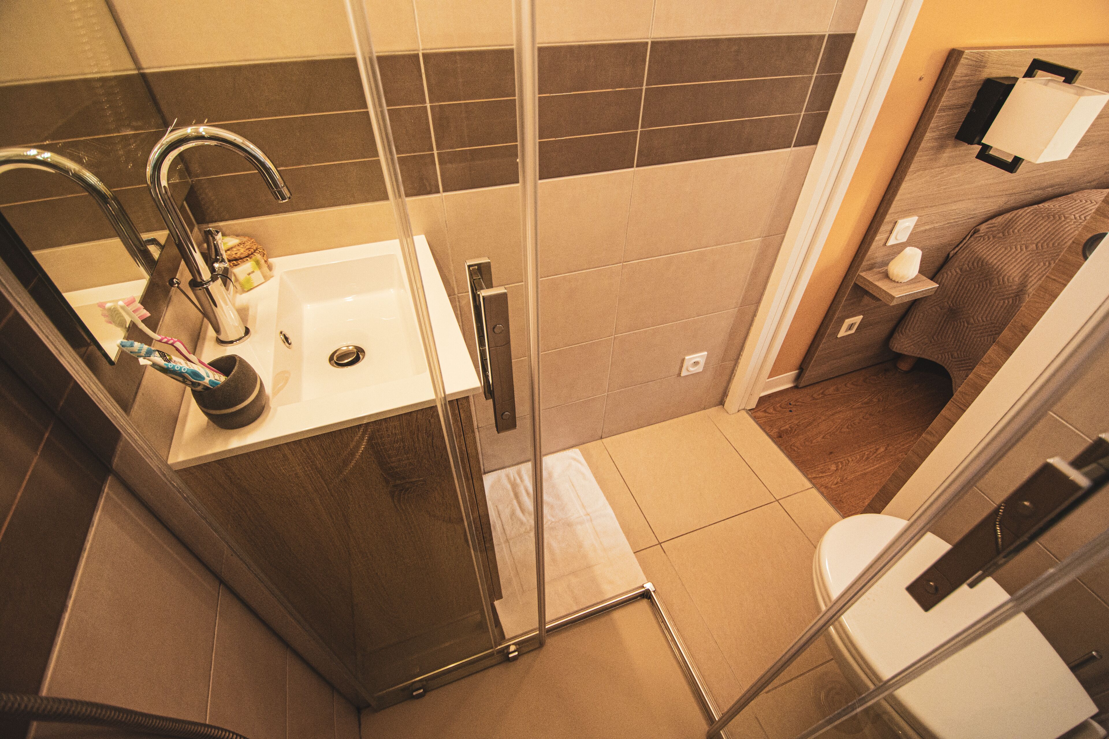 A modern bathroom with a glass shower enclosure, a white sink with a mirror, and a toilet.