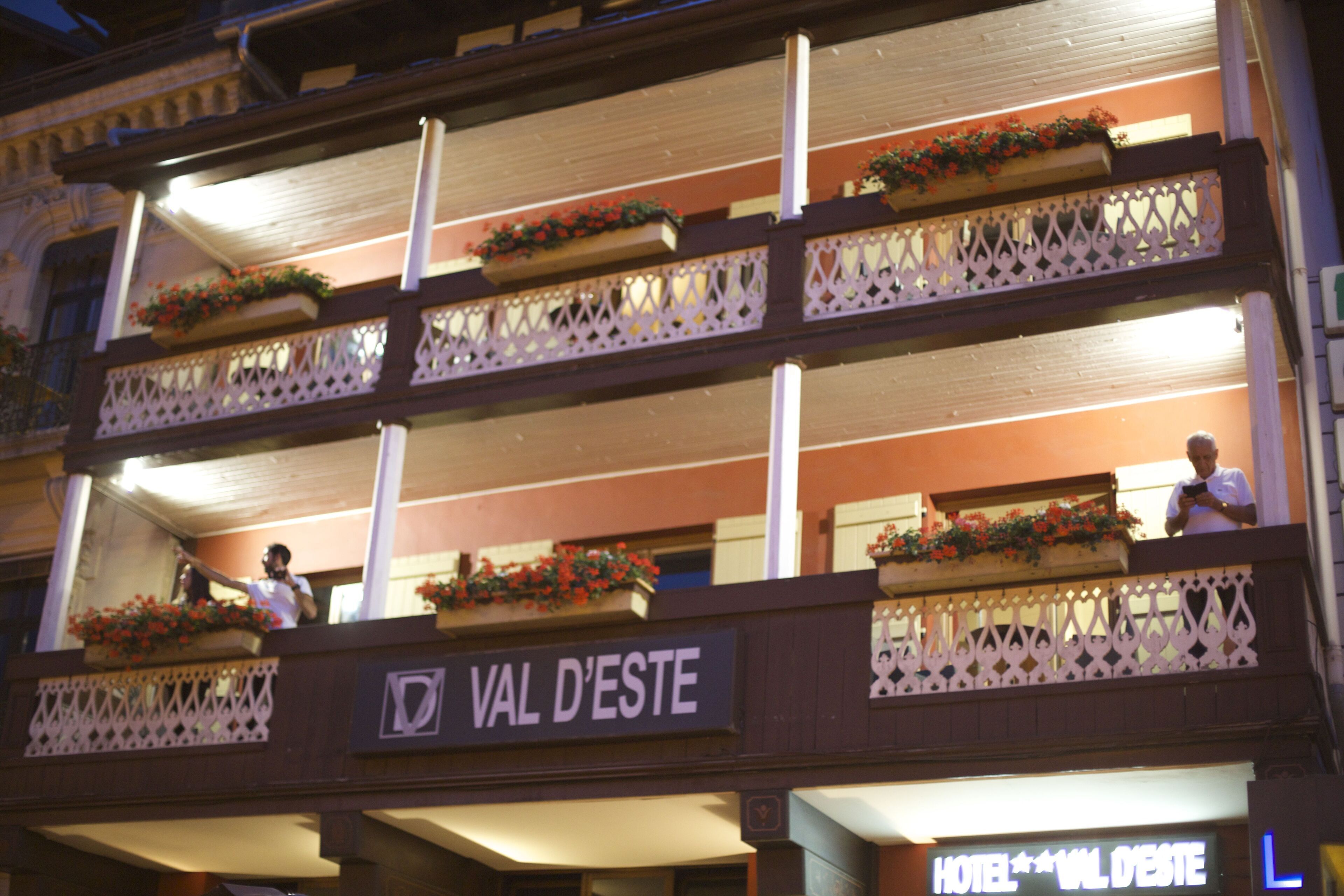 Ett hotell med balkonger som är dekorerade med blomlådor och en skylt med texten ”VAL D’ESTE”.