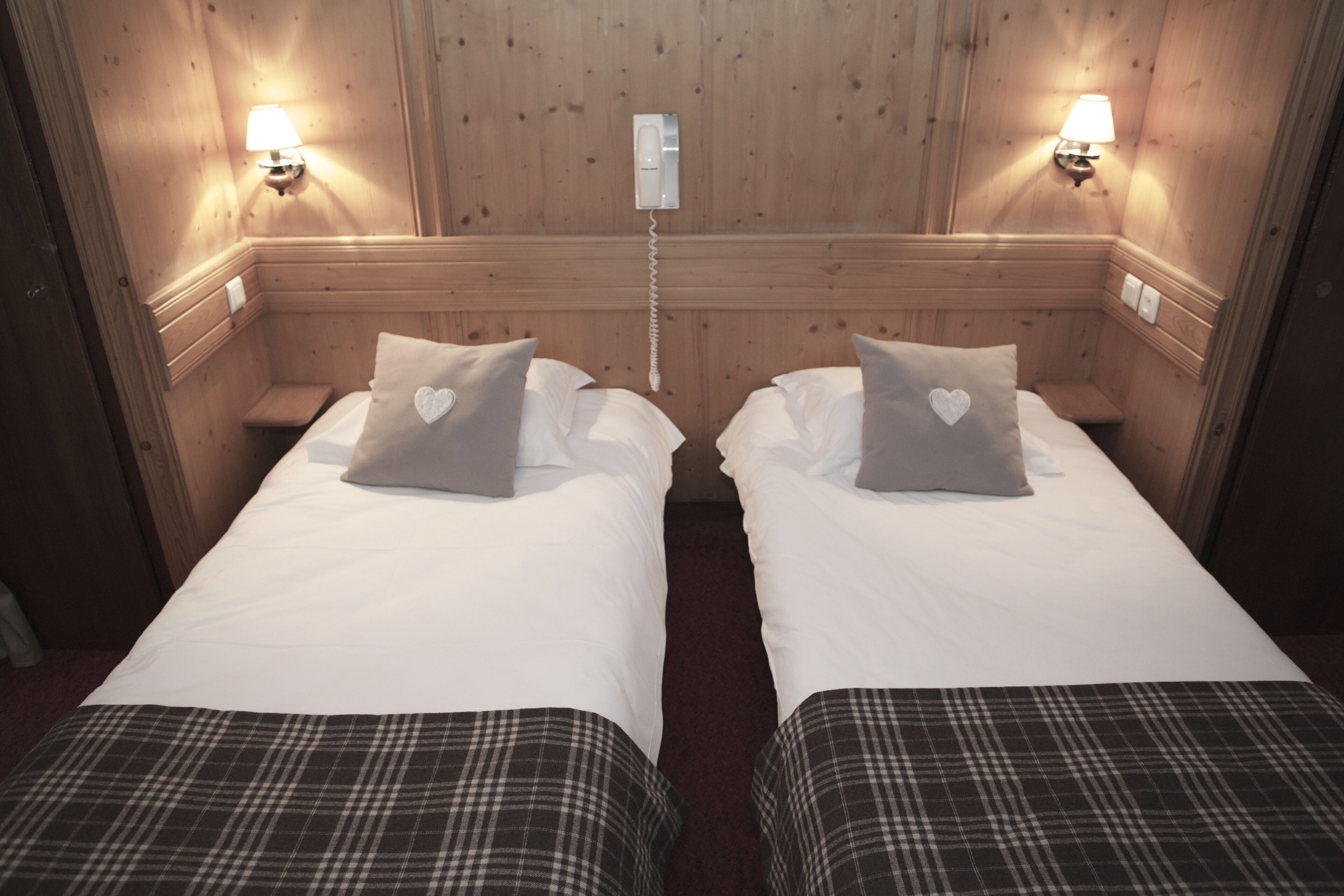 Ein Zimmer mit zwei Betten, jedes mit Kissen und Nachttischlampe.