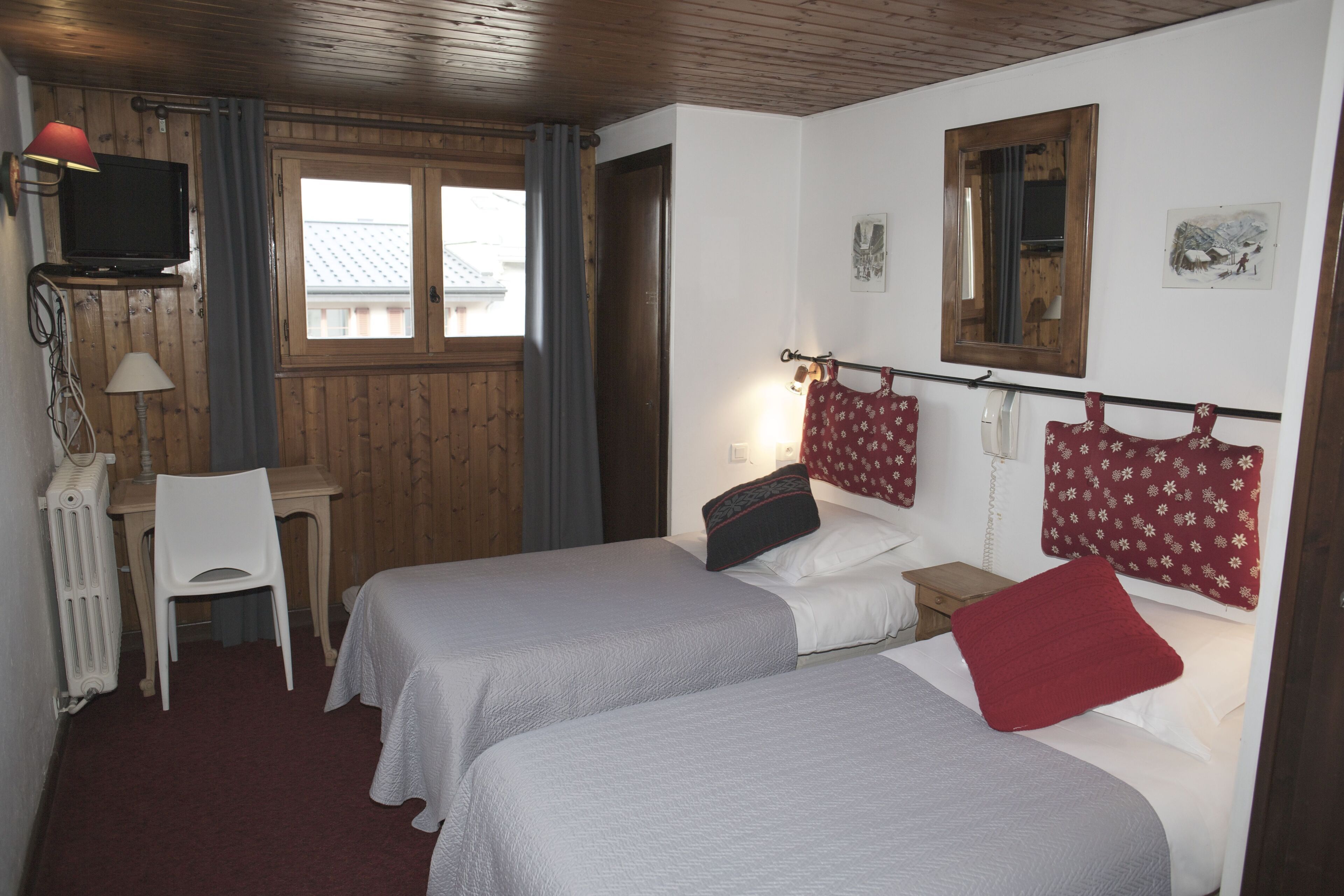 Une chambre avec deux lits, un bureau, une chaise, une télévision et une fenêtre.
