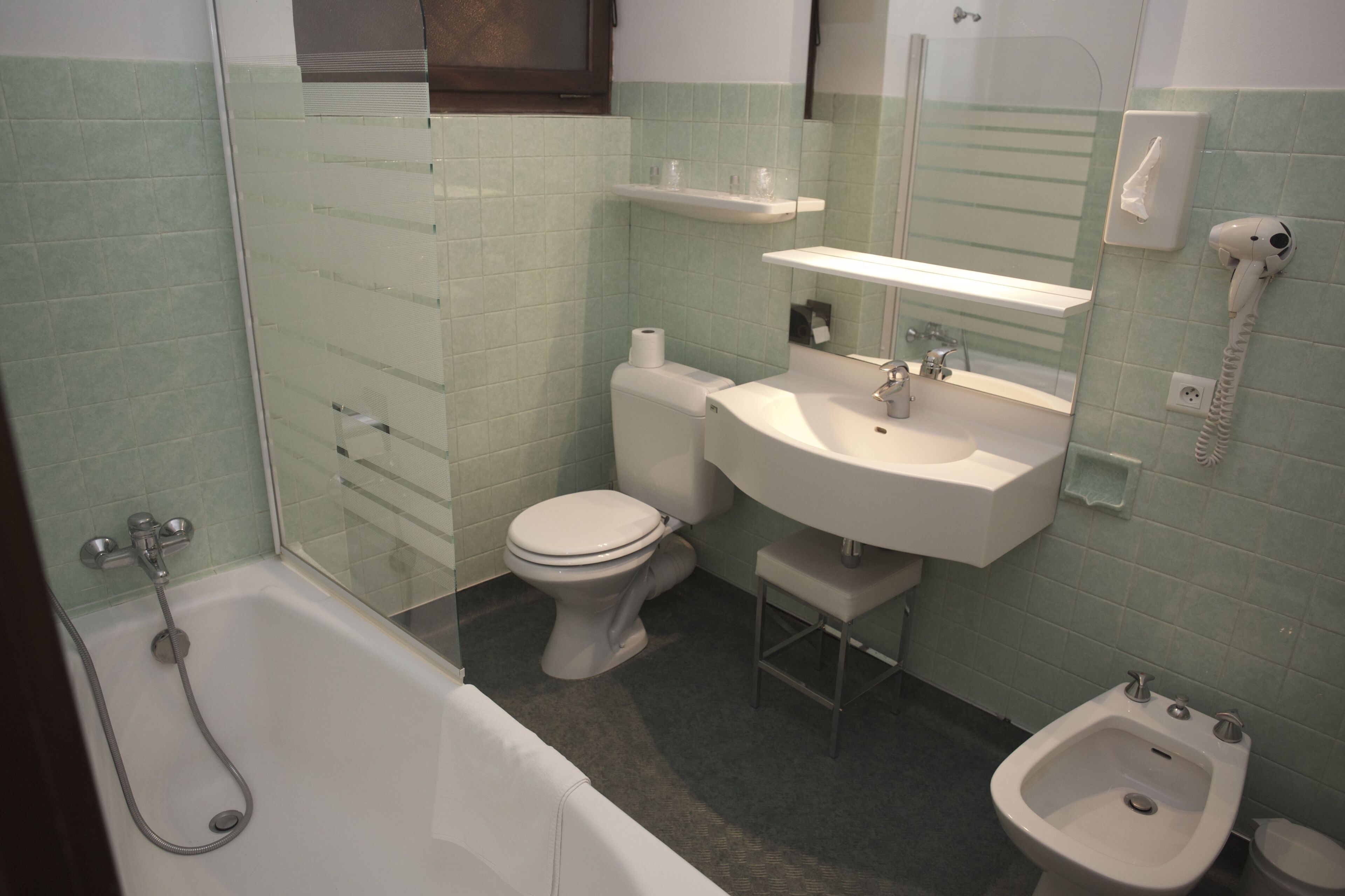 Ein Badezimmer mit Badewanne, Toilette, Bidet, Waschbecken und Spiegel.