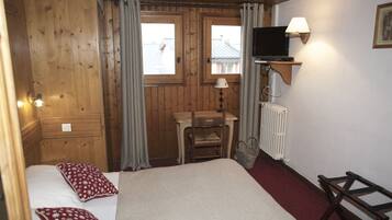 A wooden room with a bed, a desk, a chair, a television, and a window.