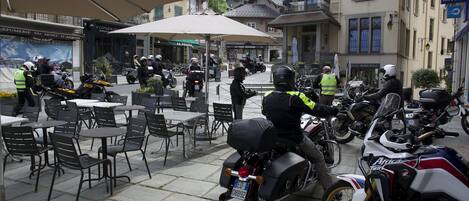 A café with outdoor seating, a motorcycle parked in front, and a building with a sign reading "Hotel de Ville".