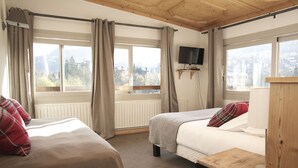Une chambre avec deux lits, une télévision et une vue sur les montagnes.