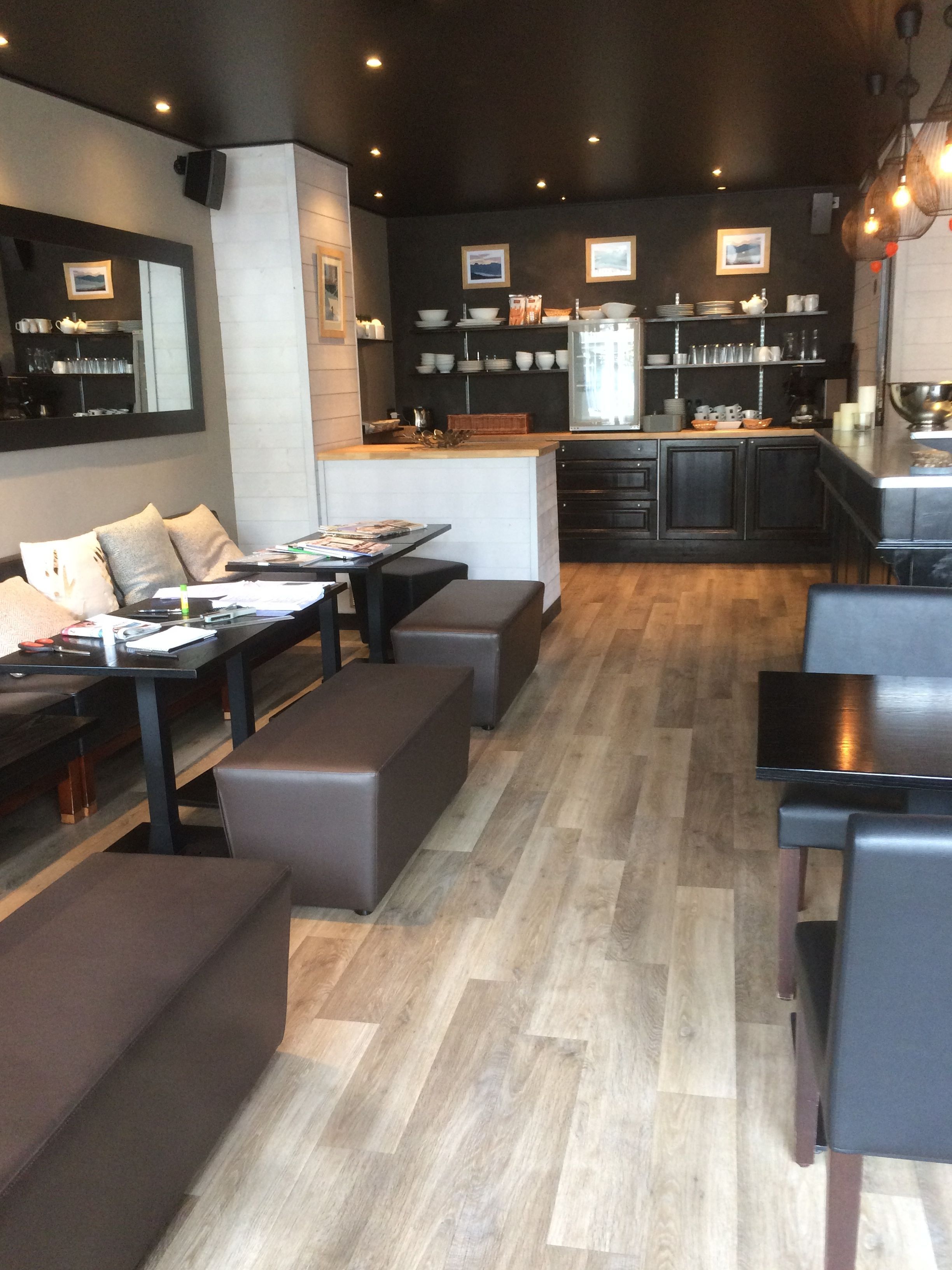 A modern kitchen with dark cabinetry, a central island, and a dining area with a sofa and benches.