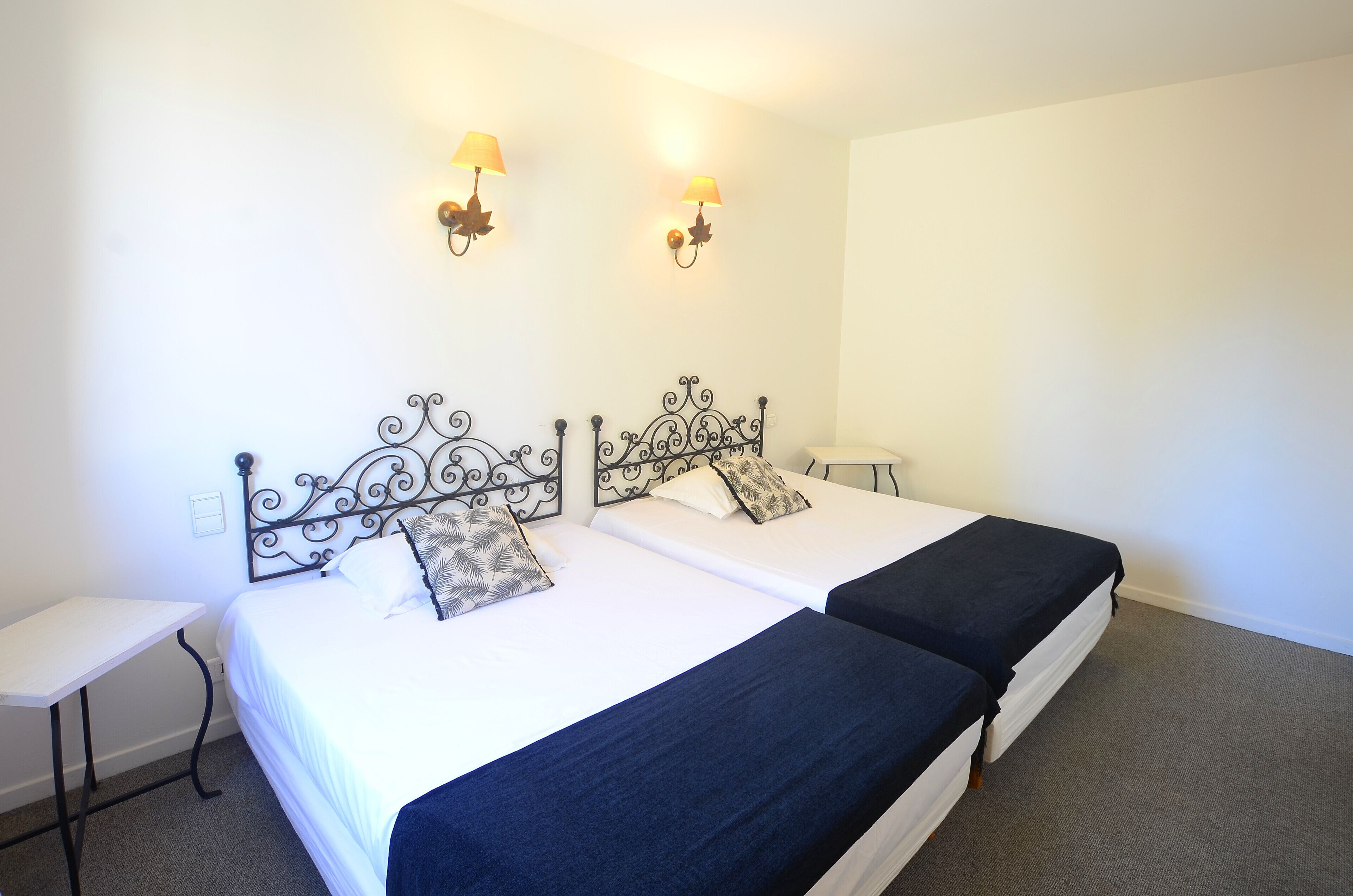 A double bed with a decorative headboard, two bedside lamps, and a small table beside the bed.