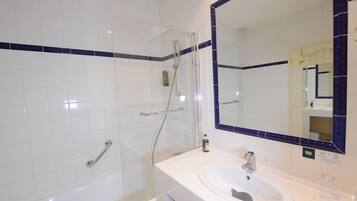 Une salle de bain équipée d’une baignoire, d’un lavabo et d’une douche avec une porte en verre.