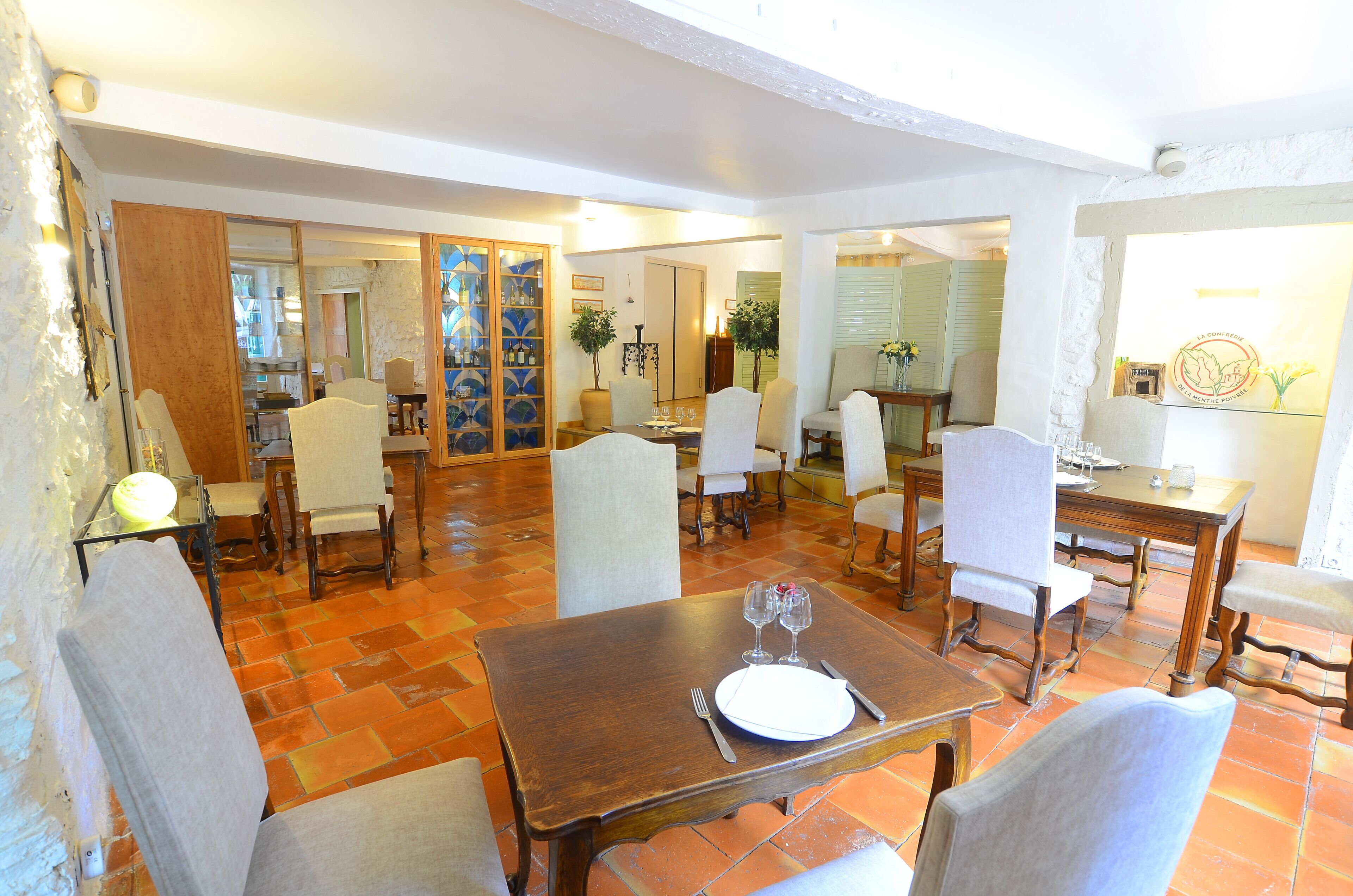 Un comedor con varias mesas y sillas, suelo de baldosas y una vitrina de vidrio con botellas.