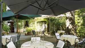 An outdoor dining area with round tables, chairs, and umbrellas.