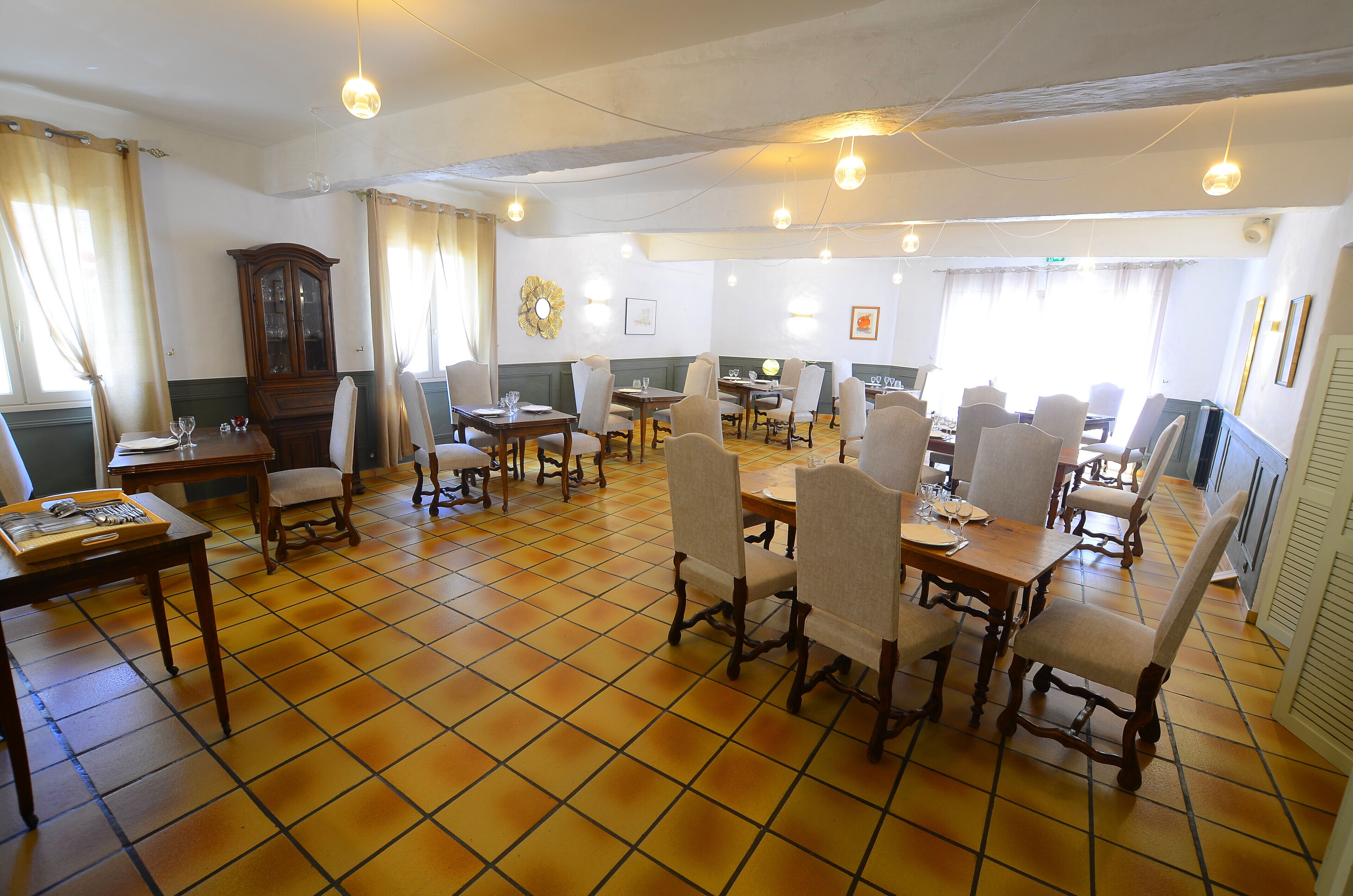 Un comedor con varias mesas y sillas, un armario de madera y piso de baldosas.