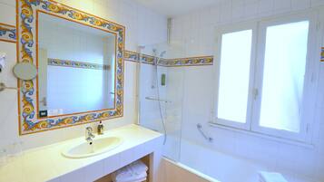 A bathroom with a white sink, mirror, and shower area.