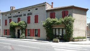 A building with red shutters and a sign that reads "hotel restaurant du midi".