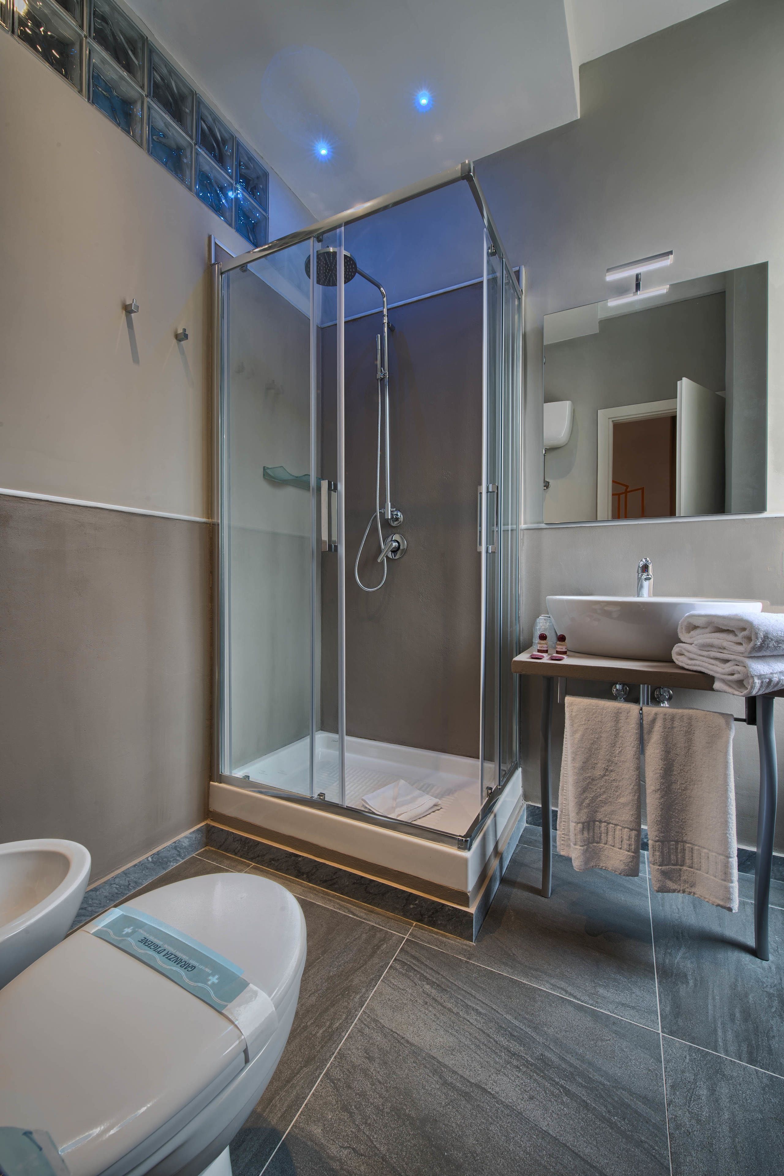 Ein modernes Badezimmer mit einer Duschkabine, einer Toilette, einem Waschbecken mit Spiegel und einem Handtuchhalter.