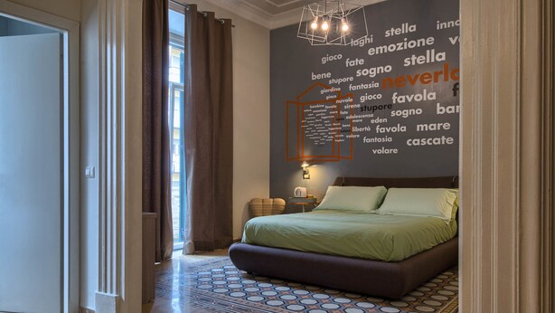 A modern bedroom with a large bed, a word cloud wall, and a patterned floor. - The Pope's Window (Rome)