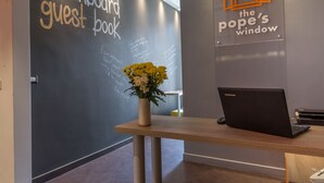 A reception area with a blackboard guest book, a laptop, and a vase with flowers. - The Pope's Window (Rome)