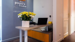 A reception area with a desk, a laptop, and a vase of yellow flowers. - The Pope's Window (Rome)