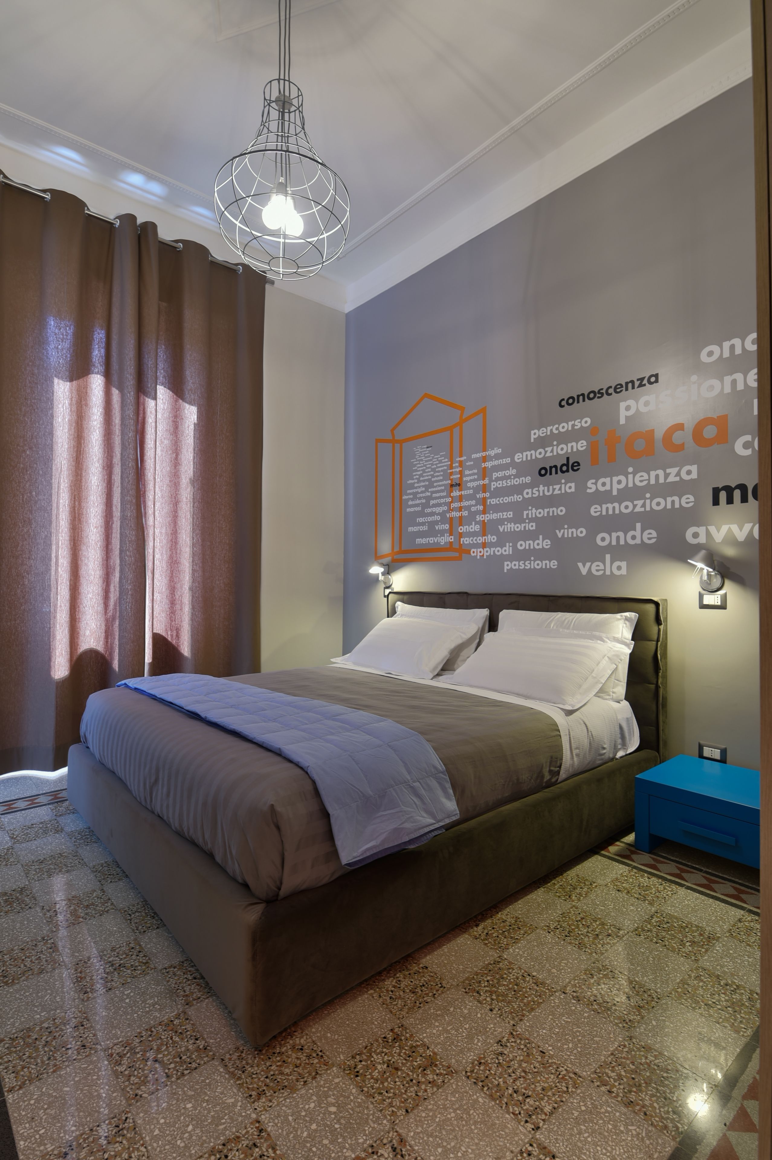 A modern bedroom with a bed, a nightstand, a wall-mounted light, and a decorative light fixture.