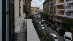 A street view with buildings, cars, and a clear sky. - The Pope's Window (Rome)