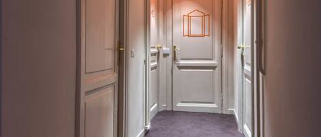 A narrow hallway with white doors and a carpeted floor.