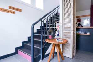 Een trap met houten borden waarop kamer nummers 21 en 22 staan, een receptiebalie en een klein tafeltje met een decoratief object.