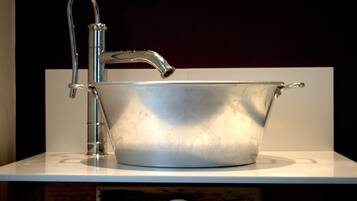 Ein metallenes Waschbecken mit einem einzelnen Wasserhahn auf einer weißen Arbeitsplatte.