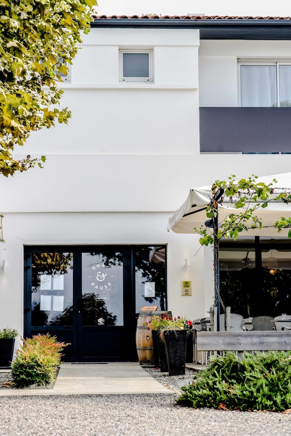 A modern building with a black door, outdoor seating, and potted plants.