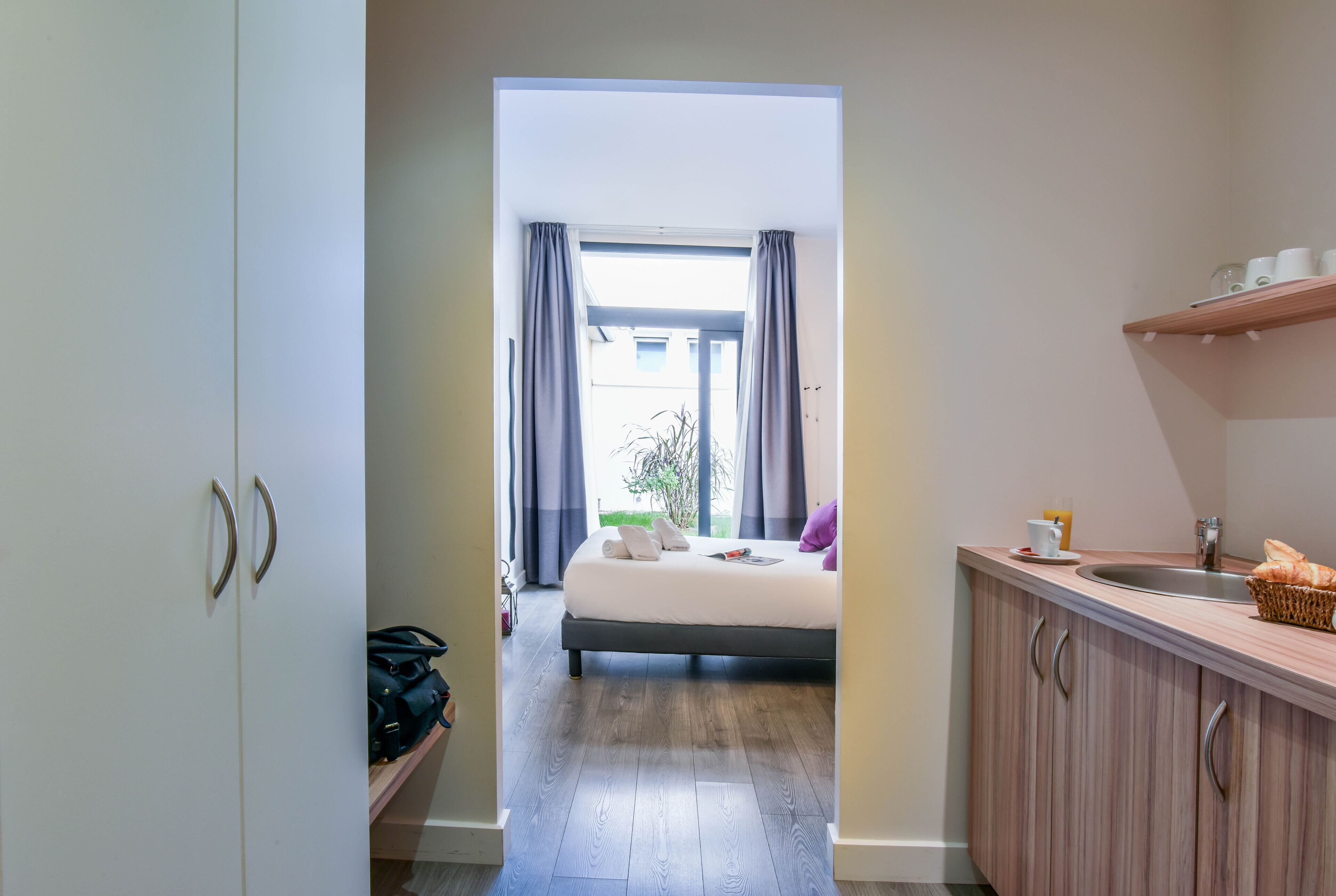 Een hotelkamer met een bed, een badkamer en een kitchenette.