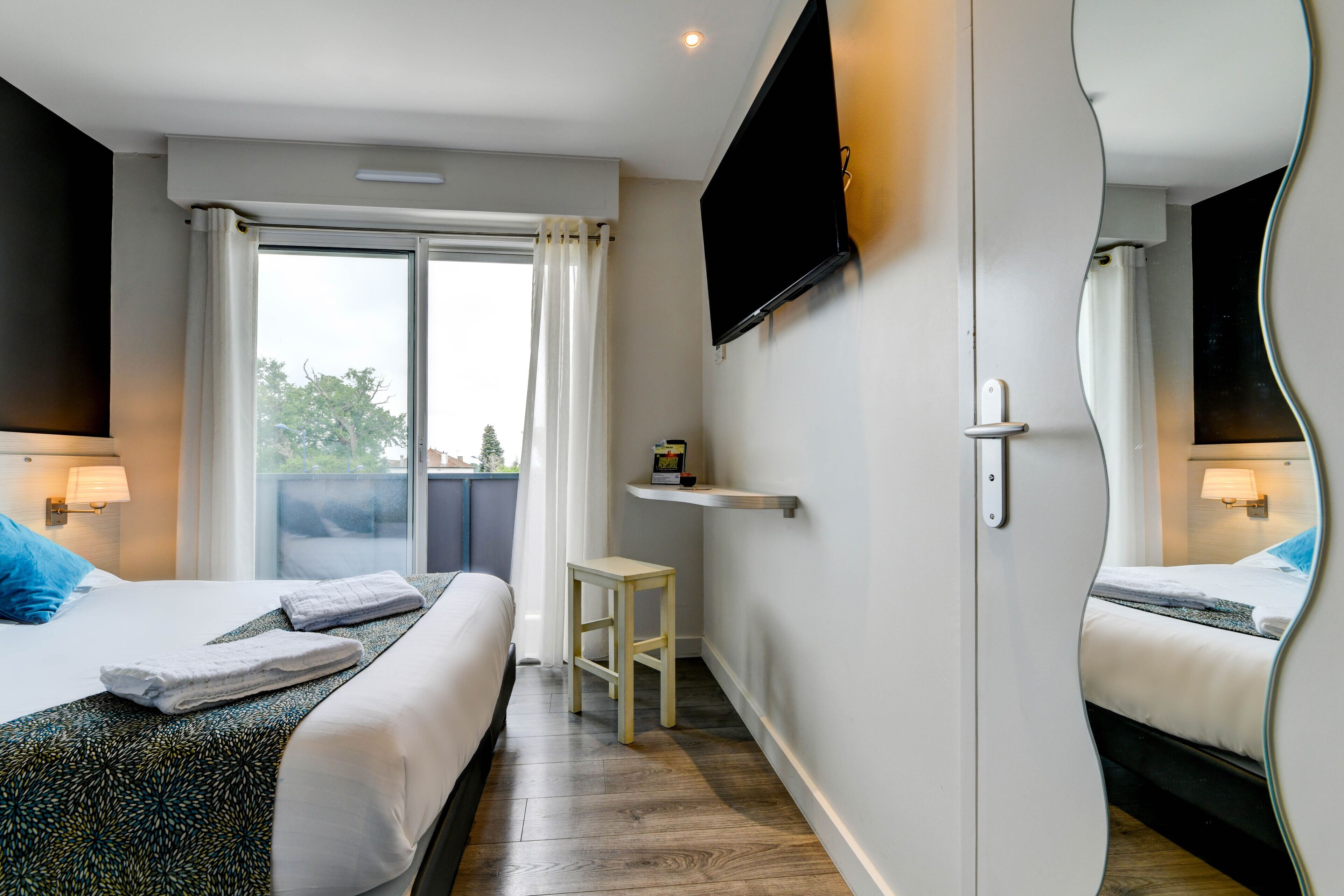 Habitación de hotel con dos camas, un televisor, una mesita y una ventana con cortinas.