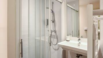 A modern bathroom with a glass-enclosed shower, a white sink, and a large mirror.