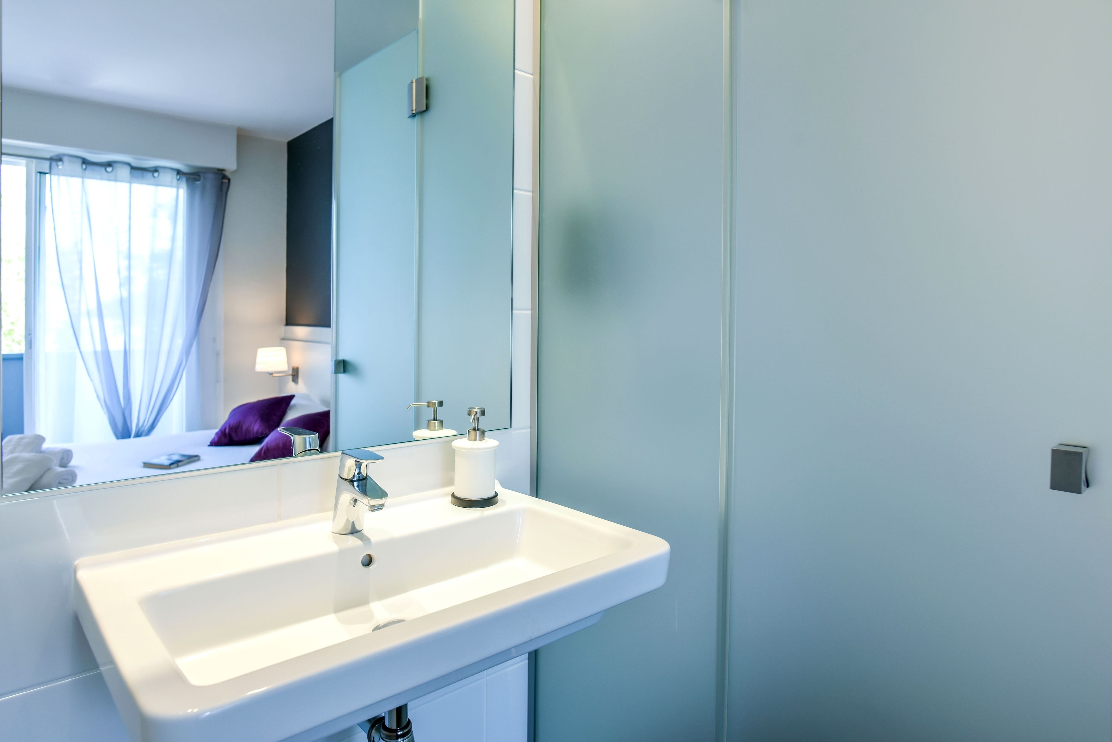 Un baño moderno con un lavamanos blanco, un espejo y un inodoro.
