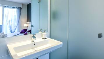 Un baño moderno con un lavamanos blanco, un espejo y un inodoro.