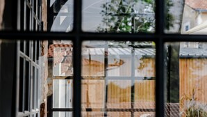 Ein Gitterfenster, durch das ein Gebäude und ein geparktes Auto sichtbar sind.