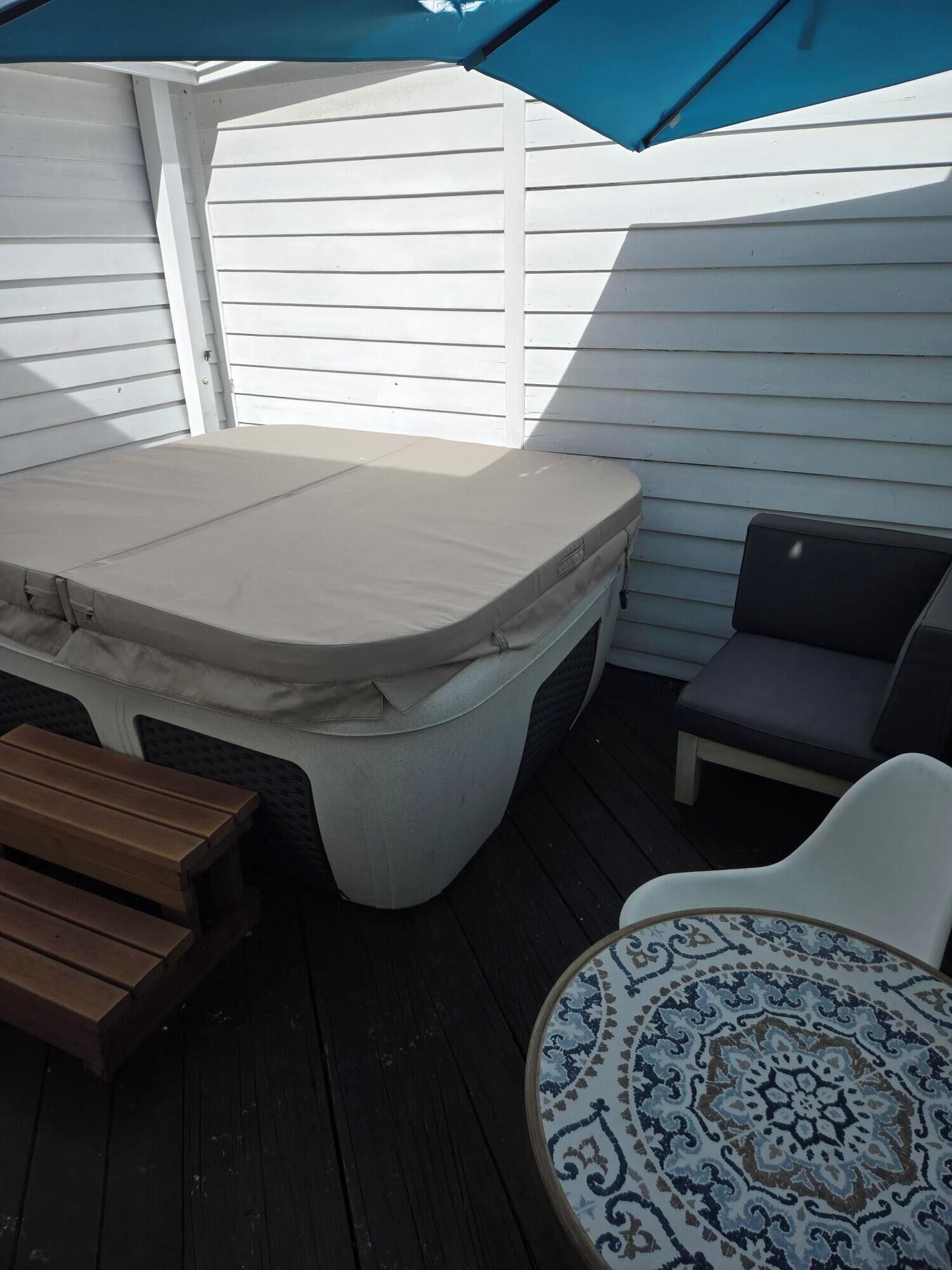 A covered outdoor seating area with a table and benches, a patterned table, and a wooden bench.