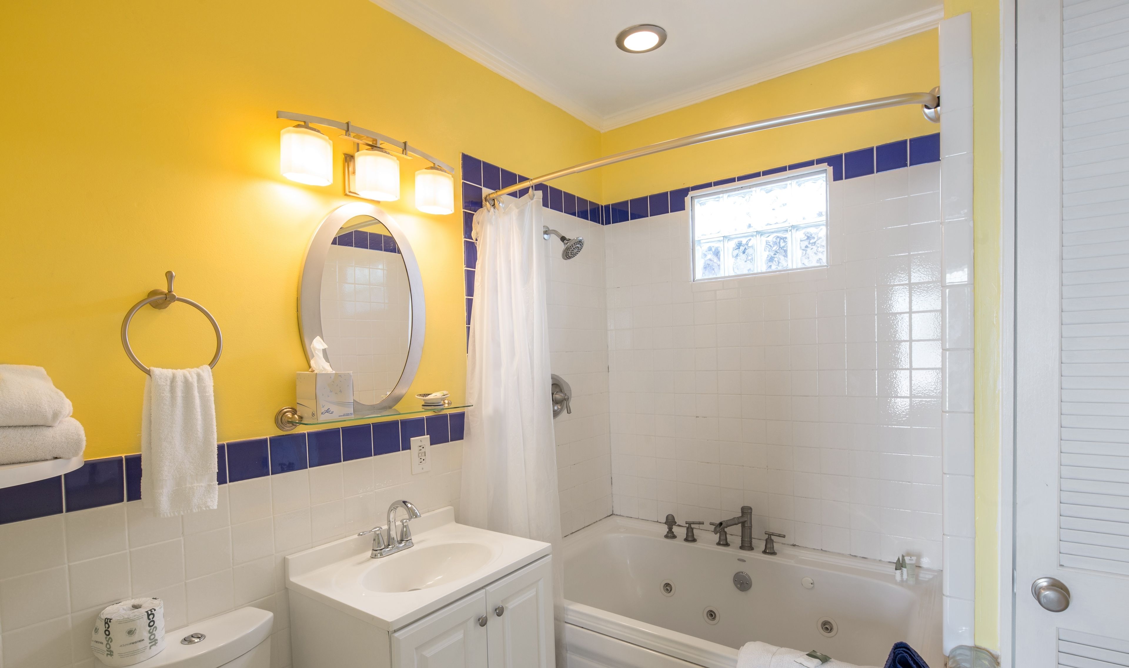 A bathroom with a yellow wall, a white sink, a bathtub, and a shower curtain.