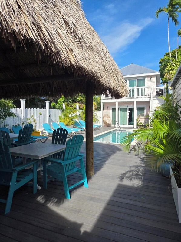 A wooden deck with a thatched roof, outdoor seating, and a pool. - Wicker Guesthouse (Key West)