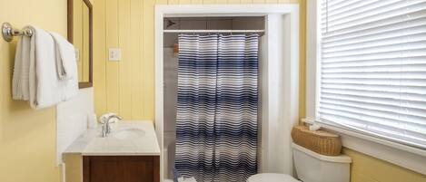 A bathroom with a white sink, a toilet, and a shower curtain with a wavy pattern.